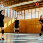 A young interracial volleyball team is practicing on indoor court.