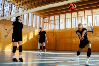 A young interracial volleyball team is practicing on indoor court.