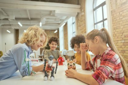 Development. Joyful diverse children sitting at the table, looking at technical toys full of details