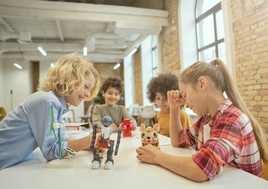 Development. Joyful diverse children sitting at the table, looking at technical toys full of details