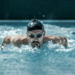 dynamic and fit swimmer in cap breathing performing the butterfly stroke