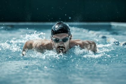 dynamic and fit swimmer in cap breathing performing the butterfly stroke