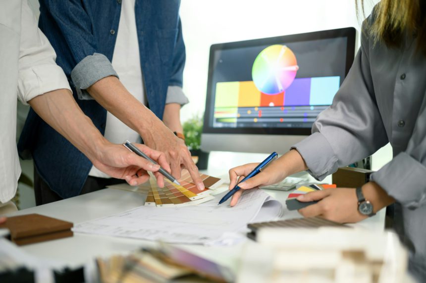 Group of creative people choosing paint color and discussing interior design project at office