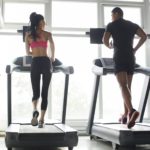 Young couple exercising on treadmills in gym
